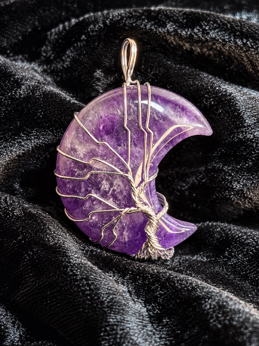 Purple Amethyst crescent moon pendant with handcrafted gold-toned Tree of Life wire wrapping and hanging loop, photographed on black velvet.