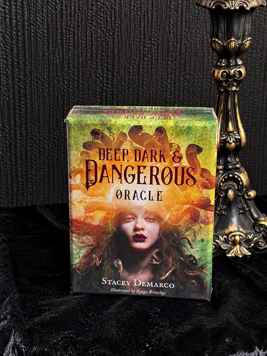 Deep, Dark & Dangerous Oracle by Stacey Demarco, illustrated by Kinga Britschgi, featuring a dark-haired woman surrounded by serpents in orange and green artwork.