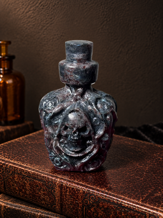 Dark polished garnet poison bottle carving with raised scrollwork and skull detail