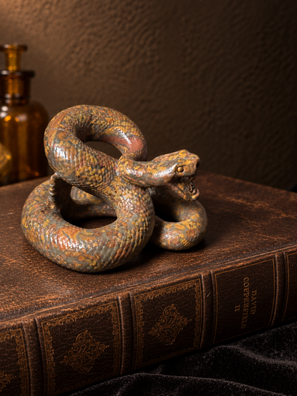 Side view of a coiled jasper snake carving showing detailed scales, open mouth and orange, brown and grey stone patterning.