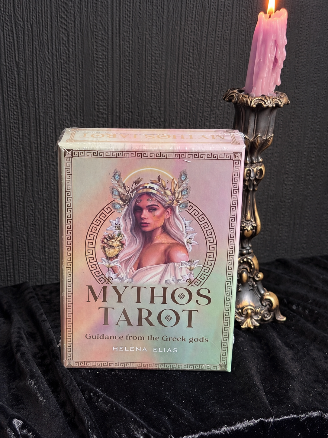 Mythos Tarot by Helena Elias, pastel pearlescent tarot box featuring a Greek goddess with golden laurel crown, flowers and classical Greek border detailing.