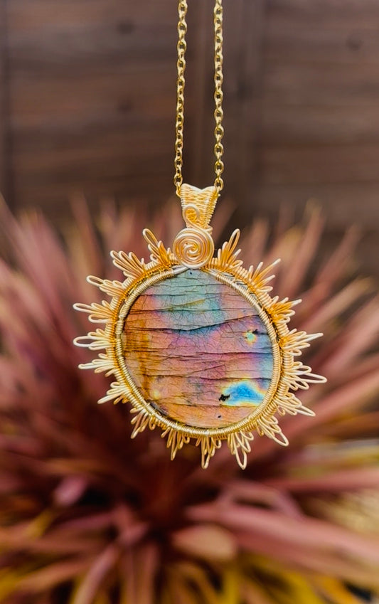 Large rainbow Labradorite statement pendant with pink, gold, blue and violet flash, surrounded by intricate gold-tone sunburst wirework.