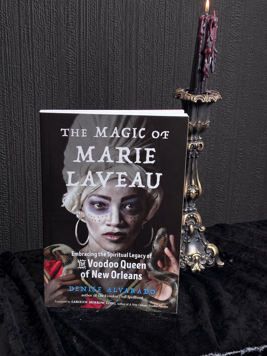 The Magic of Marie Laveau by Denise Alvarado, paperback book featuring a portrait of a woman with white headwrap, hoop earrings and a snake.