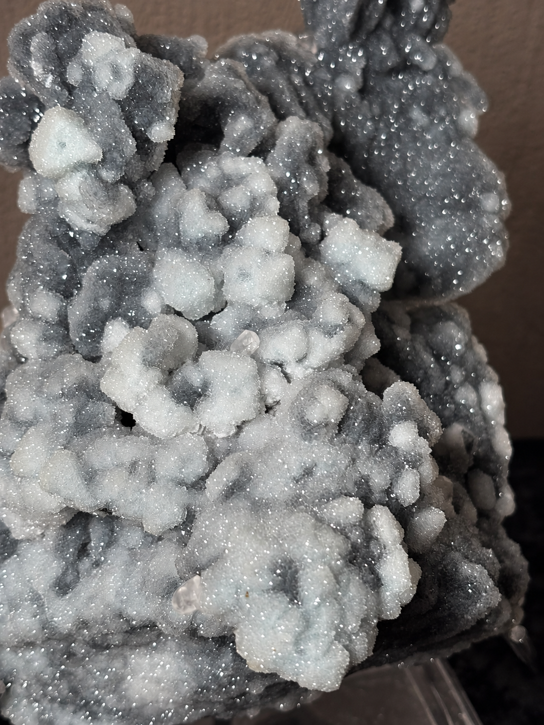 Close-up of sparkling grey and pale blue botryoidal formations on a Xianghualing chalcedony, fluorite and calcite specimen.