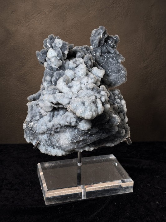 Large blue-grey and charcoal chalcedony mineral specimen with rounded crystalline formations displayed on a clear acrylic-based stand.